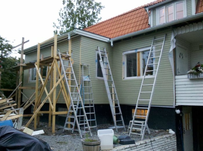Scaffolding and ladders against a house under renovation, constructed with 45x95 and 195x45 wooden planks.