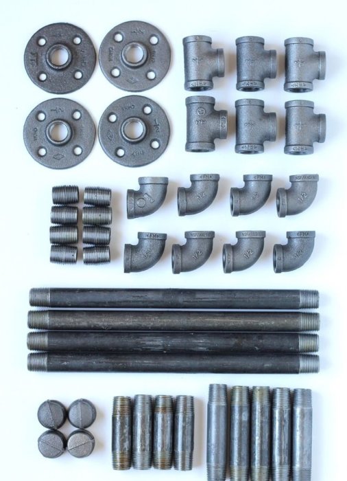 Steel pipes and fittings, including elbows, tees, and flanges, laid out on a surface.