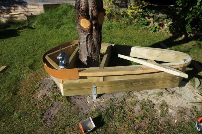 Byggprojekt med kurviga masonitremsor runt en trädslump liknar en njure eller avokado.