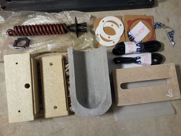 Komponenter för kamininstallation inklusive packningar, isolersten och kylslinga.