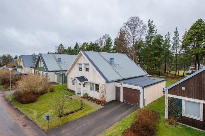 Vy över en radhuslänga med sadeltak i Skoghall, tillverkade 1972, i en lugn gatubild med omgivande träd.