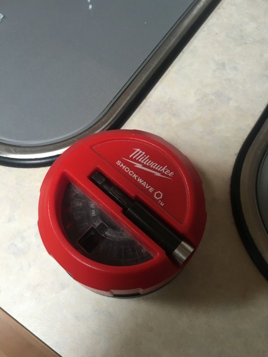 Röd och svart Milwaukee Shockwave magnetisk puck med bits på ett bord.