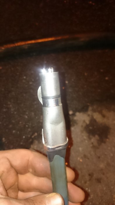 Hand håller en ofullständigt ihopkopplad pumpkontakt med synliga metallstift och delvis ansluten slang.