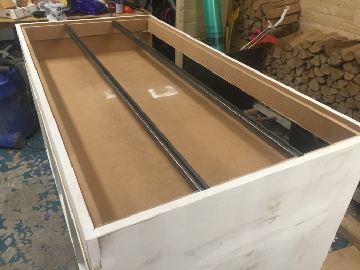 Träbyggnad med fyrkantsprofiler monterade i ramverket och förstärkning i en verkstadslokal.