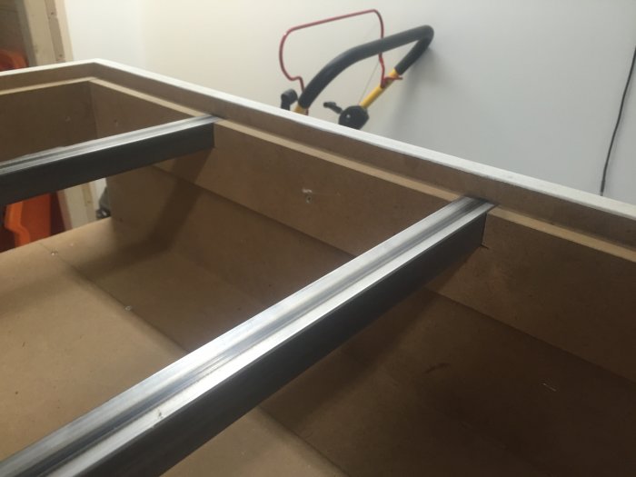 Fyrkantsprofiler monterade i träram som förstärkning för att förhindra skevhet, verktyg i bakgrunden.