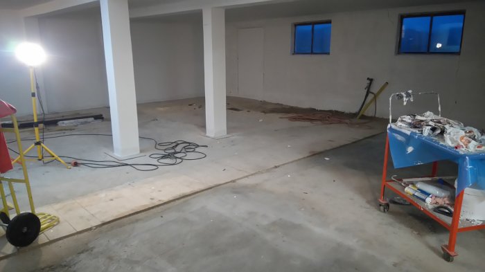 Inomhusbild av en 80 kvadratmeter stor isolerad ladugårdslokal med betonggolv, pelare, och gamla 2-glasfönster.