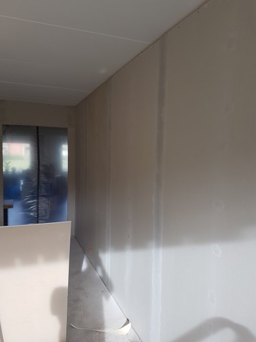 Vägg med nygjorda gipsskarvar som är spacklade och redo för provmålning.