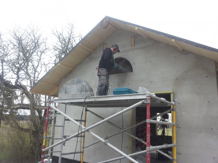 Byggarbetare monterar ram och förbereder installation av halvmånefönster på ett hus under konstruktion.