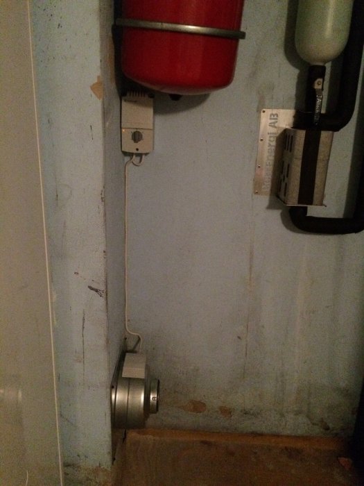 Ventilationssystem med en installerad silvrig fläkt, synlig kabeldragning och en röd behållare ovanför.
