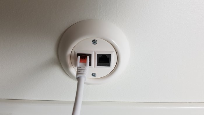 Nätverksuttag på vägg med ansluten Ethernet-kabel uppe på en vind.