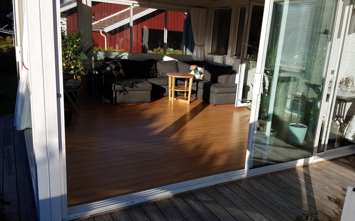 Uterum med Kronotex Ocean Oak laminatgolv och grå soffgrupp under soligt väder.