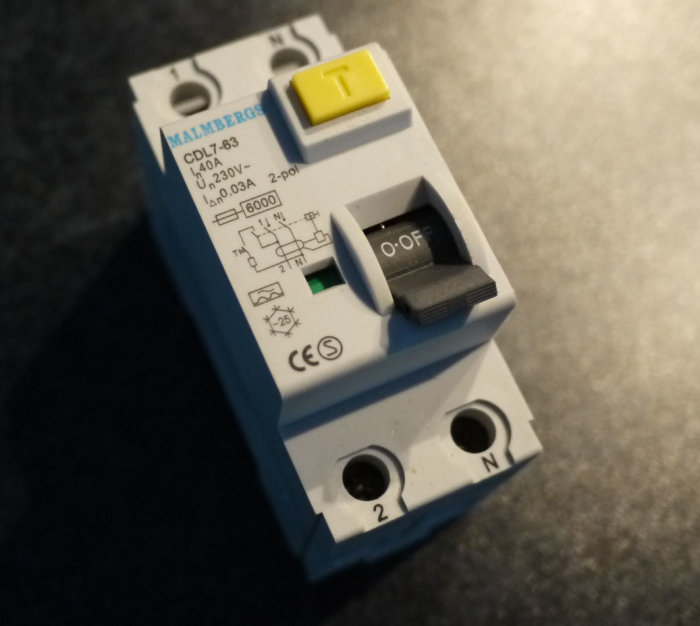 En grå överspänningsskydd eller relä med tekniska specifikationer och on/off-switch.