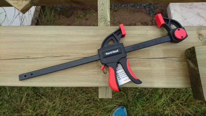 Tving från Hard Head på träplanka, med röda och svarta handtag samt etikett.