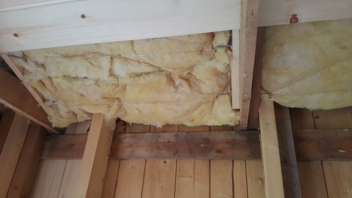 Isolering mellan träreglar i taket på en gäststuga under renovering.