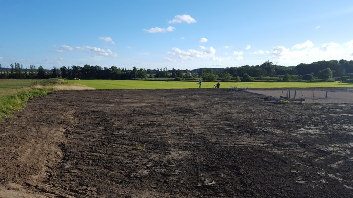 Nyplanerad tomtmark redo för byggstart med markarbeten utförda, i landsbygdsmiljö på en solig dag.