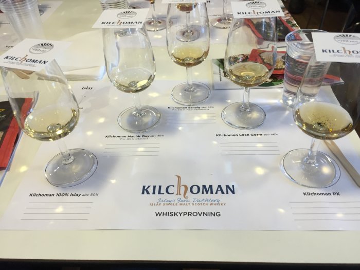 Whiskyprovning med olika sorter av Kilchoman single malt på en provningsduk, glas med whisky i förgrunden.