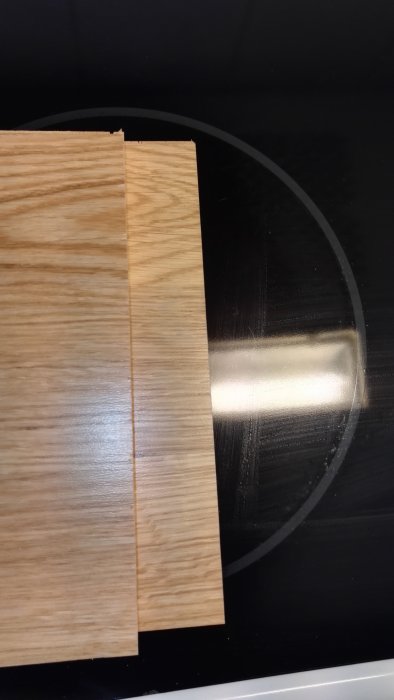 Två träskivor med olika sågade snitt, en med jämn ytlig snittyta och en med grovt genomgående snitt.