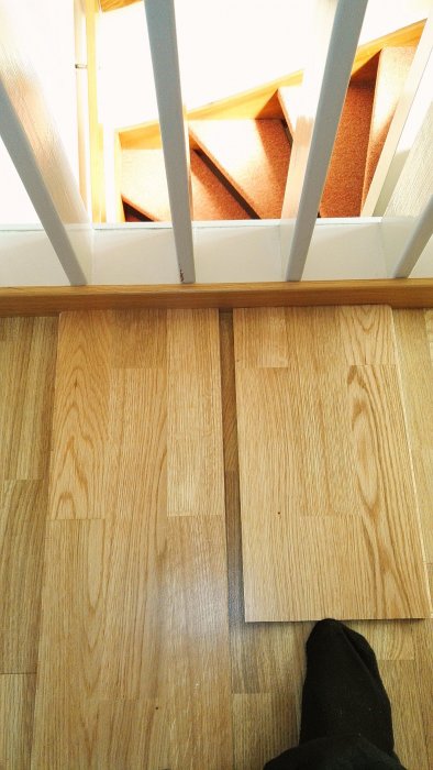 Illa passande trägolvbitar vid vit trappa, med ett misslyckat försök till rätt snitt.