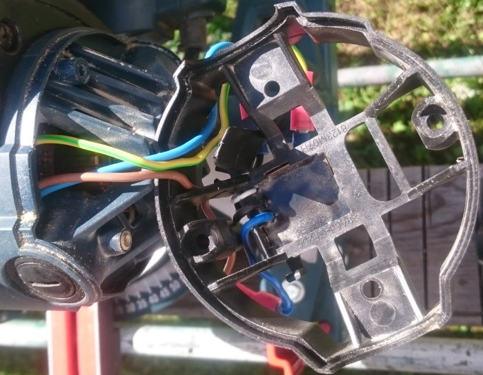 Öppet handtagsfäste med färgkodade kablar kopplade till komponenter och mjukstartmodul, mot suddig bakgrund.