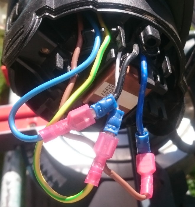 Elektriska kablar kopplade med skarvhylsor inne i ett verktygshandtag, inklusive förlängda blå och bruna kablar.