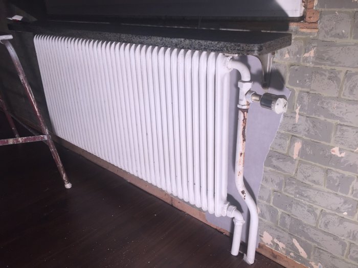 Radiator med termostat utan avstängningsventil, rör i sovrum väntande renovering.