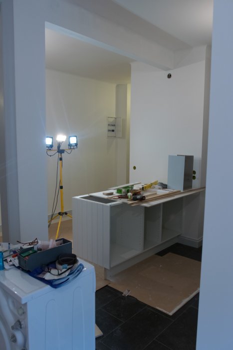 Nybyggd köksö i ett rum under renovering med arbetsmaterial och belysning.