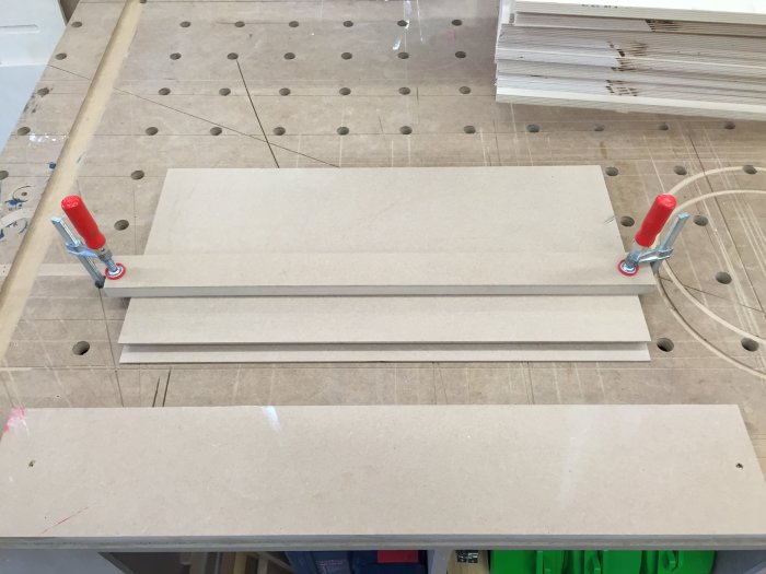 Björkplywoodskivor fastspända på arbetsbordet, redo för fräsning med handöverfräs och stödbitar.