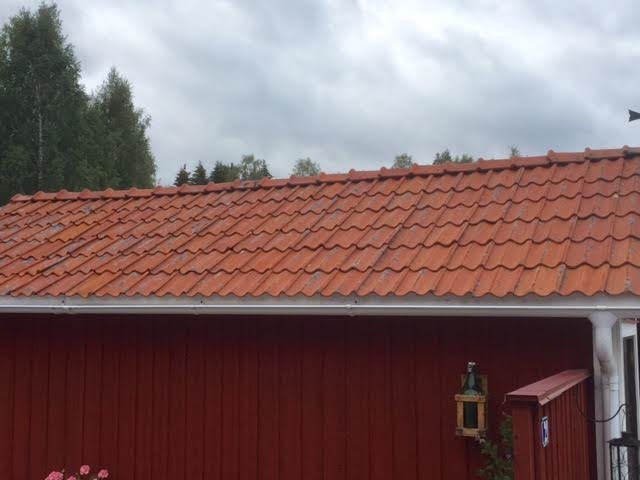 Tak med orange takpannor på rött hus, delvis behandlat med bensaltensid, skillnader i renhet synliga.