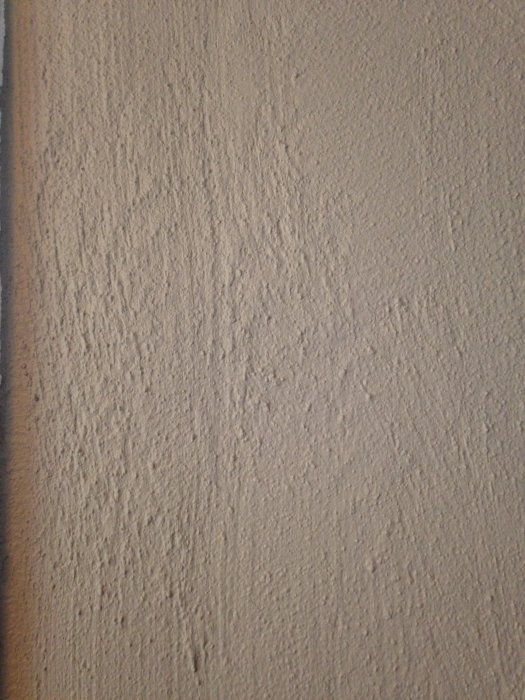 Vägg med grov struktur och ojämn målning som kan behöva bredspackling.