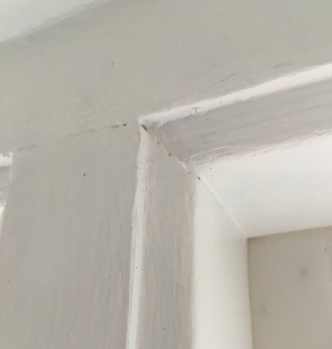 Närbild av ett vitt fönsterhörn där spröjs möter karm, synliga smutsfläckar och gerning.