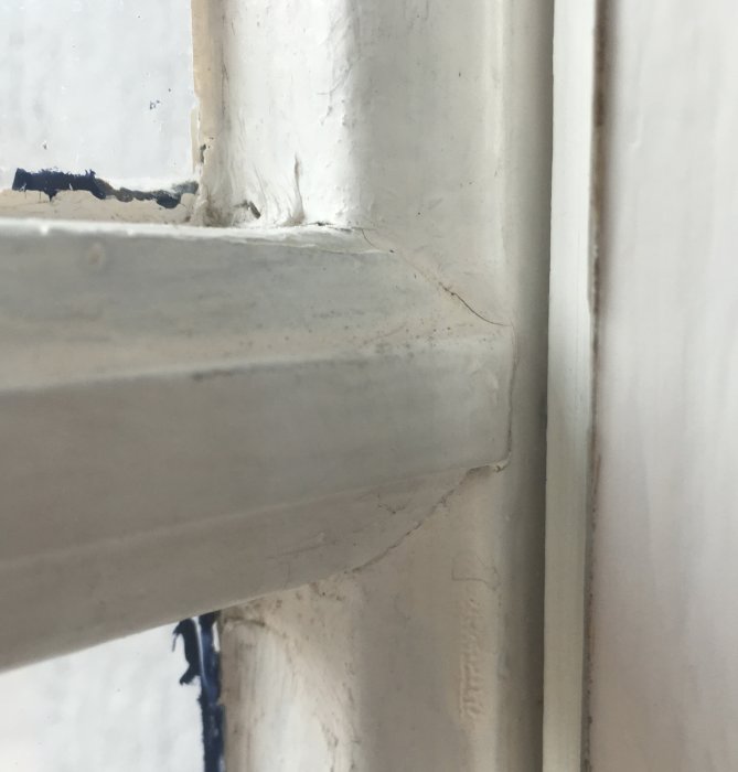 Närbild på hörn av fönsterkarm med smutsig spröjs och gerad profil.