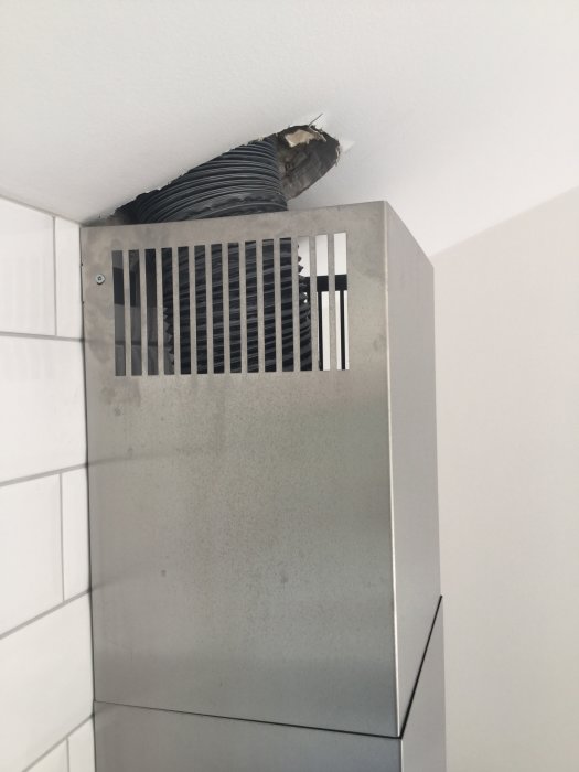 Rostfri Siemens fläktkåpa som inte når upp till snedtaket med synlig ventilationsrör.