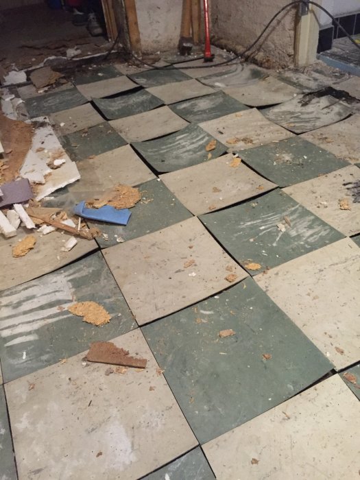 Renovering eller skada, trasiga gröna och vita plattor på golv med skräp.