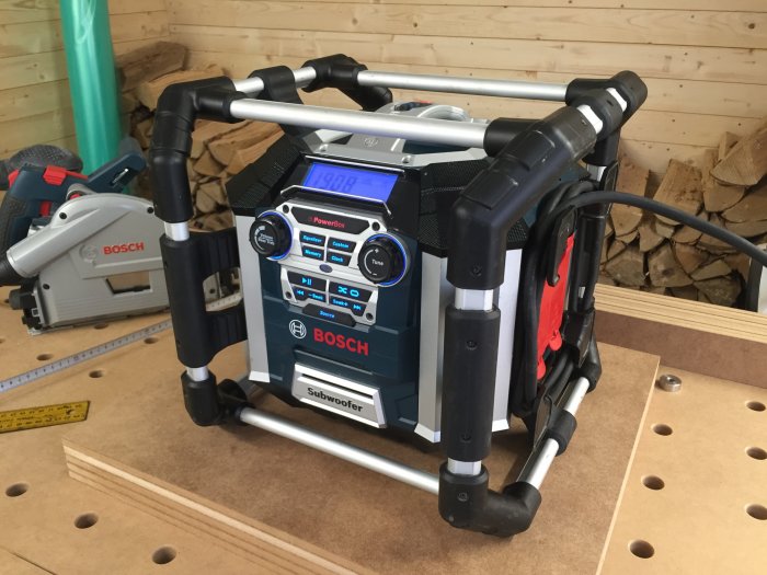 En Bosch GML 50 byggradio med 18V batteri och Bluetooth på arbetsbänk i trähantverksmiljö.