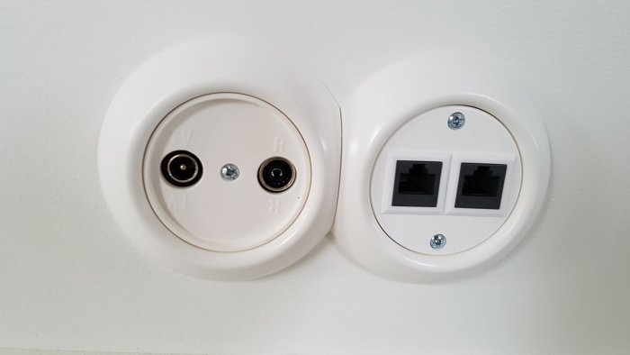 Nymonterade vita antennuttag och nätverksuttag på en vägg.