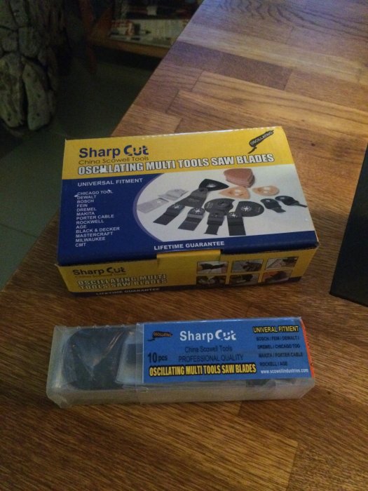 Paket med oscillerande multiverktygssågblad från Sharp Cut och löften om livstidsgaranti på en träbordsskiva.