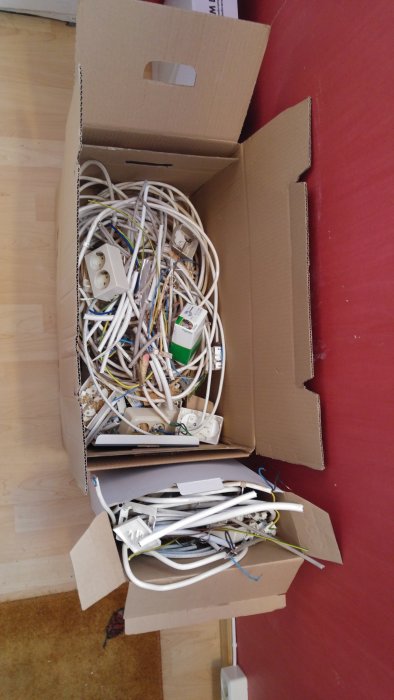 En kartong full med gammal elektrisk utrustning och kablar, som tagits bort i samband med renovering.