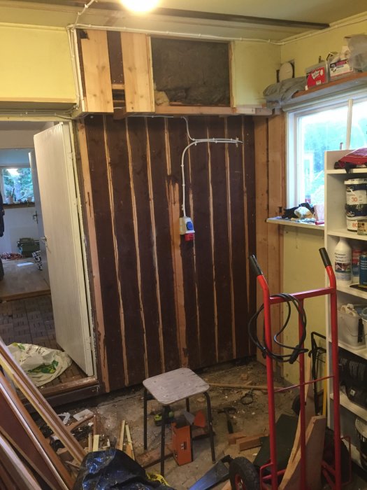 Renoveringsprojekt i garage med borttagen garderob, synliga träreglar och isoleringsmaterial på väggen.