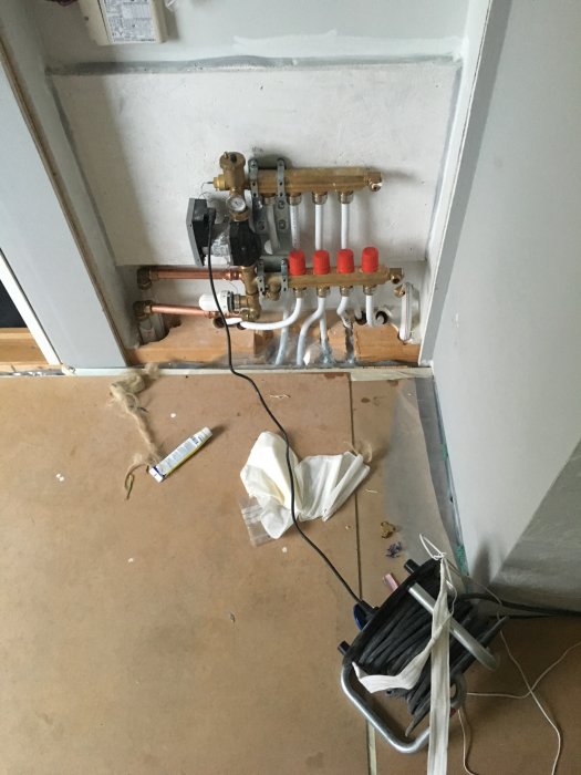 Installationsvy av bergvärmesystem med shuntar och rörkopplingar på en väggarbetsplats.