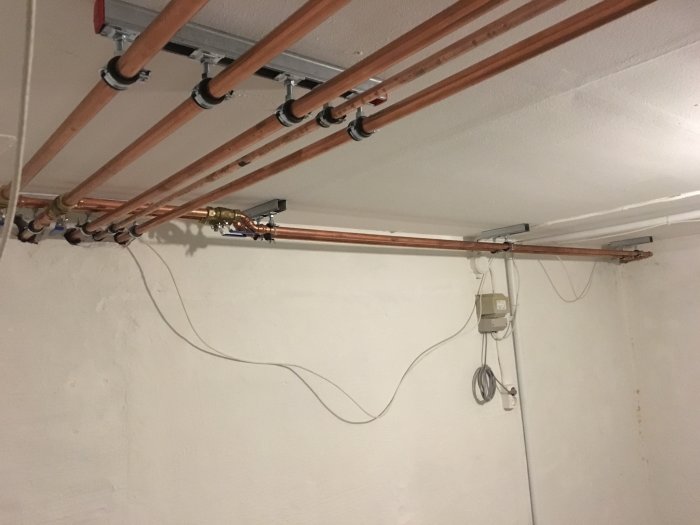Installation av kopparledningar och shuntar för bergvärme nästan färdigställd i källartak.