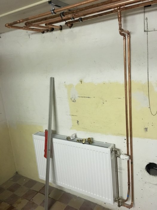 Nyinstallerade kopparrör och radiator i ett renoveringsprojekt för uppvärmningssystem.