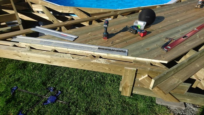 Pågående arbete på en trädäcksrenovering med sågat trall, verktyg och felkapad ytterplanka.