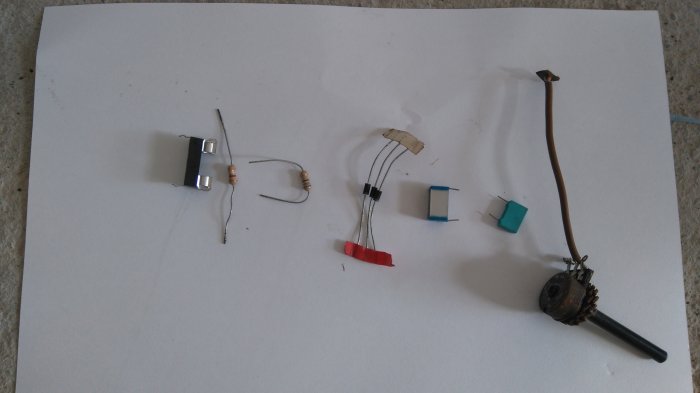 Elektronikkomponenter och potentiometer uppvisade på papper, indikerande reparationsförsök.