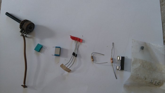 Elektronikkomponenter inklusive potentiometer och motstånd utspridda på ett vitt papper.