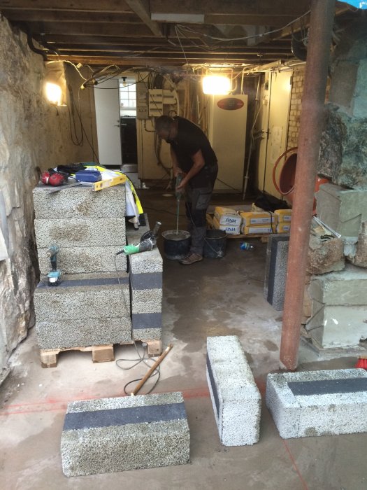 Person som förbereder för murning i ett pågående byggprojekt, blandar bruk och armeringsjärn syns.