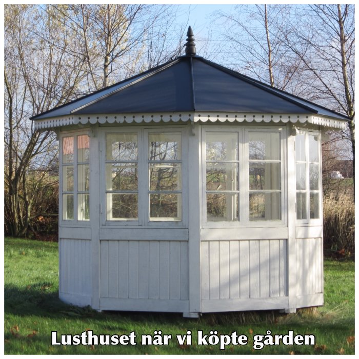 Vitt lusthus med blått tak och många fönster i en trädgård, beskrivet som initialt hyggligt skick.