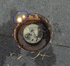 Närbild av takbrunn med skada och applicerad tätningsmassa på papptak.