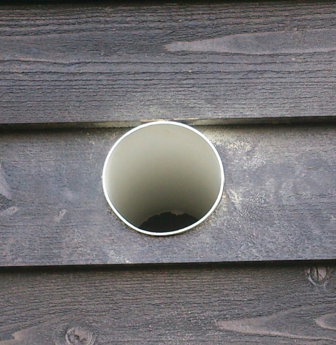 Ventilationsrör från Marley på 100mm i en vägg med svart fjällpanel.