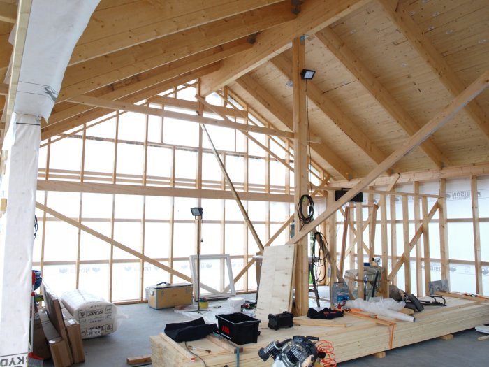 Nytt bygge med trästomme och nylagt, slätt betonggolv omgivet av verktyg och byggmaterial.