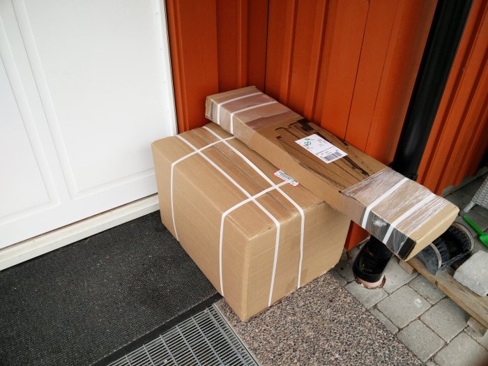 Paket levererade och lämnade utanför en dörr, bundna med packsnören och skyddade med plast.